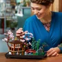 Lächelnde Frau justiert rosa Kirschblütenbaum am LEGO-Modell des friedlichen Gartens mit Pavillon und roter Brücke