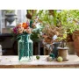 Bouquet LEGO coloré dans un vase en verre turquoise, posé sur une table en bois avec bobine de ficelle et ciseaux