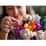 Vue rapprochée d'une femme assemblant délicatement une fleur LEGO rose du bouquet coloré avec ses doigts