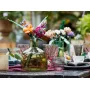 Bouquet LEGO coloré avec roses, gerberas et lavande dans un vase vert sur une table décorée avec verres et bougies