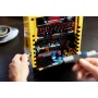 Gros plan sur la borne d'arcade LEGO PAC-MAN avec écran noir pixelisé, manette de jeu et figurines colorées, mains en action