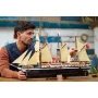 Homme admirant le navire LEGO L'Endurance avec ses trois mâts, voiles beiges et coque noire détaillée sur une table