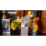 Scène intérieure avec figurines LEGO : homme aux cheveux bouclés lisant un journal près d'une femme rousse à lunettes