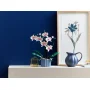 Orchidée LEGO avec fleurs roses et blanches dans pot rayé bleu sur étagère blanche, mur bleu en arrière-plan Orchidée LEGO avec fleurs roses et blanches dans pot rayé bleu sur étagère blanche, mur bleu en arrière-plan