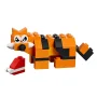 Renard LEGO orange et noir avec rayures, yeux blancs et nez gris, accompagné d'une petite construction rouge et blanche Renard LEGO orange et noir avec rayures, yeux blancs et nez gris, accompagné d'une petite construction rouge et blanche