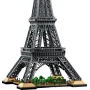 Construction LEGO de la tour Eiffel gris foncé avec base beige et petits arbres verts à sa base, vue d'ensemble sur fond blanc