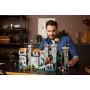 Homme souriant assemblant le château LEGO avec tours grises, murailles et figurines de chevaliers sur une table Homme souriant assemblant le château LEGO avec tours grises, murailles et figurines de chevaliers sur une table