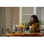 Femme assemblant le set LEGO Fondcombe sur une table en bois, montrant les bâtiments elfiques avec tour et feuillage automnal Femme assemblant le set LEGO Fondcombe sur une table en bois, montrant les bâtiments elfiques avec tour et feuillage automnal
