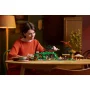 Femme en pull rouge construisant le set LEGO de la Comté avec maisons de hobbits, figurines et dragon volant dans un salon chaleureux Femme en pull rouge construisant le set LEGO de la Comté avec maisons de hobbits, figurines et dragon volant dans un salon chaleureux