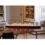 Maquette LEGO du Titanic avec coque rouge et superstructure blanche, 4 cheminées jaunes, exposée sur une table en bois dans un salon Maquette LEGO du Titanic avec coque rouge et superstructure blanche, 4 cheminées jaunes, exposée sur une table en bois dans un salon