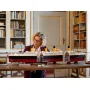 Femme admirant le modèle LEGO Titanic assemblé sur un bureau dans une bibliothèque, navire avec 4 cheminées jaunes et coque noire Femme admirant le modèle LEGO Titanic assemblé sur un bureau dans une bibliothèque, navire avec 4 cheminées jaunes et coque noire