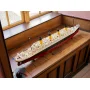 Maquette LEGO du Titanic assemblée, posée sur un meuble en bois, montrant la coque rouge, le pont blanc et les 4 cheminées jaunes Maquette LEGO du Titanic assemblée, posée sur un meuble en bois, montrant la coque rouge, le pont blanc et les 4 cheminées jaunes