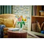 Bouquet LEGO de fleurs colorées dans un vase transparent sur une table ronde en bois, salon cosy en arrière-plan