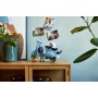 Scooter Vespa LEGO bleu clair avec figurine posée sur meuble en bois dans décor moderne avec plantes et photos