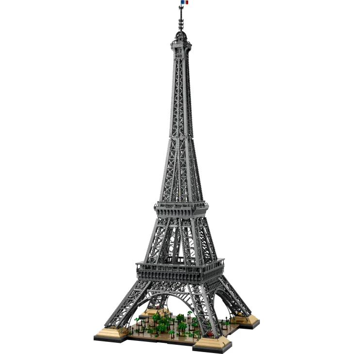 Torre Eiffel LEGO completa con estructura metálica detallada, base verde y vehículos en miniatura a sus pies sobre fondo blanco