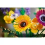 Primo piano di fiori LEGO colorati: gerbera giallo-arancio, papavero arancione e fiore rosa-viola con steli verdi