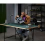Man in bruine jas leest LEGO instructiehandleiding aan bureau in moderne kantooromgeving Man in bruine jas leest LEGO instructiehandleiding aan bureau in moderne kantooromgeving